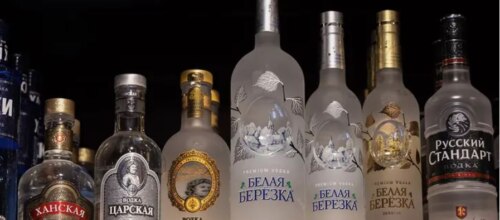 An array of liquor bottles with cyrillic label text.