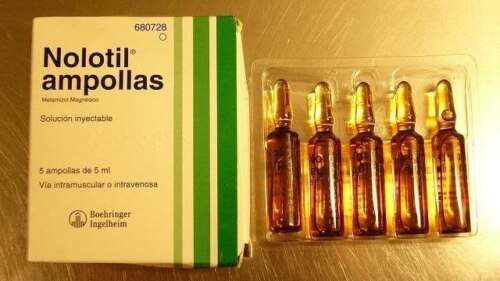 A package, labeled "Nolotil Ampoullas", next to five single-dose ampoules of the drug metamizole, brand name Nolotil.