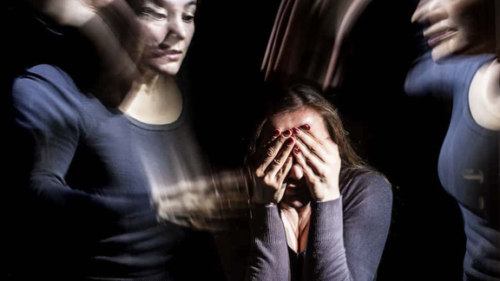 Young woman with hands over her face surrounded by distorted images of herself.