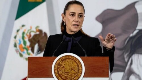 Photo by Cristopher Rogel Blanquet of Claudia Sheinbaum, President of Mexico, standing behind a lectern with the Seal of Mexico on it, her left hand gesturing.